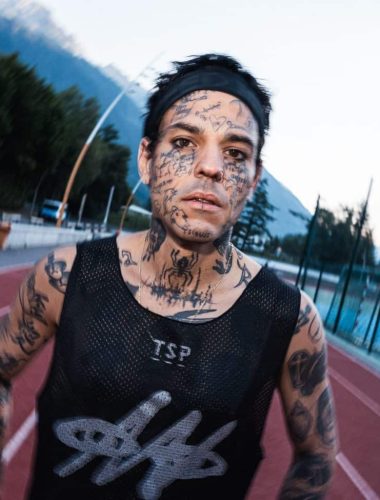 Tattooed athlete running on track.