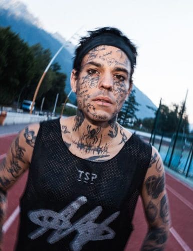 Tattooed athlete running on track.