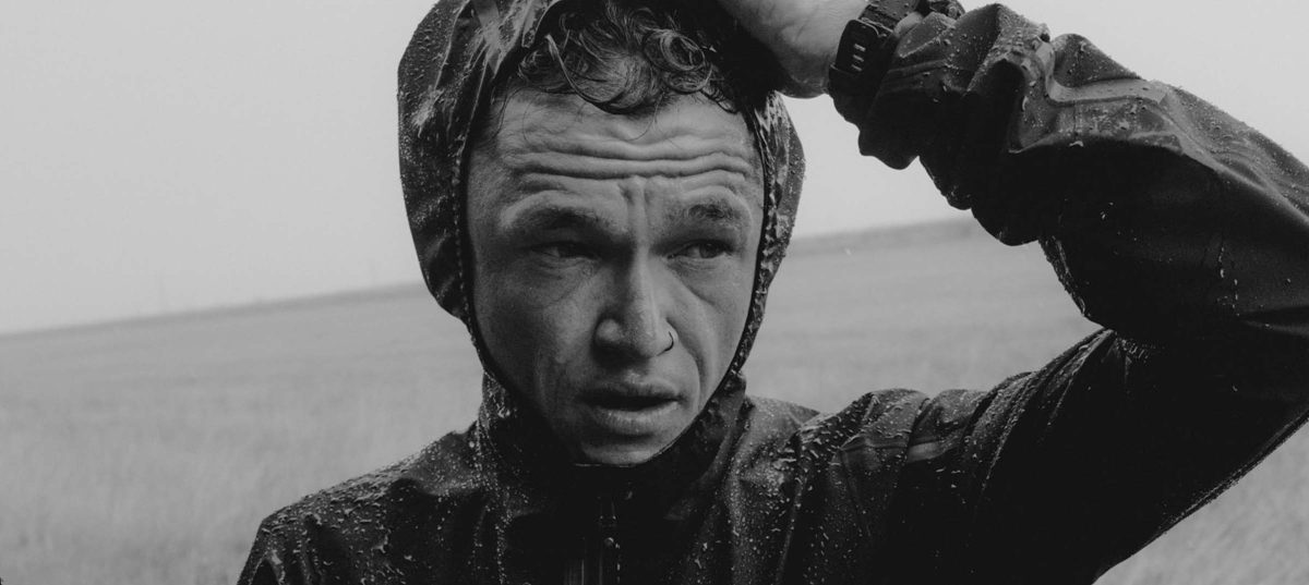 Man in raincoat, serious expression. Matt Johnson.