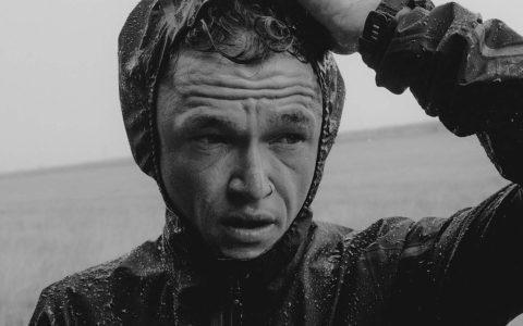 Man in raincoat, serious expression. Matt Johnson.