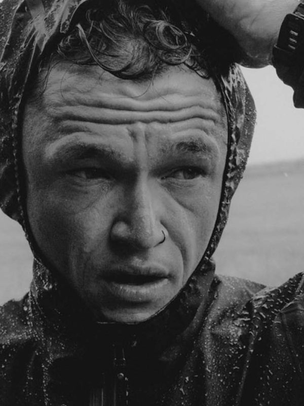 Man in raincoat, serious expression. Matt Johnson.