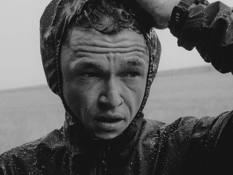 Man in raincoat, serious expression. Matt Johnson.