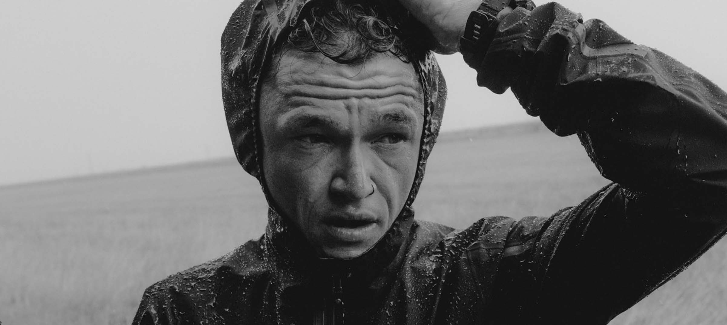 Man in raincoat, serious expression. Matt Johnson.