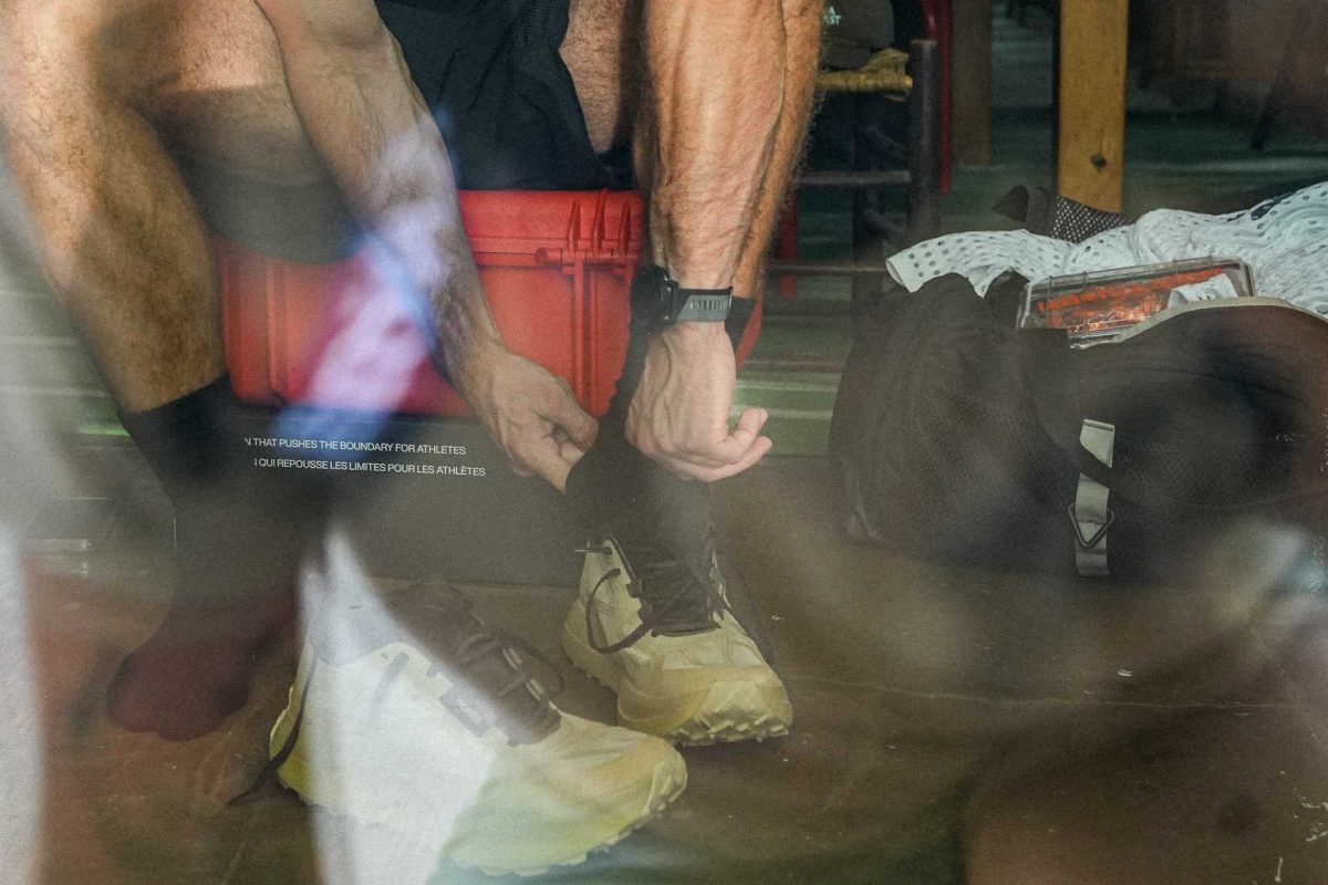 Person tying Norda 055 shoes in reflective setting.