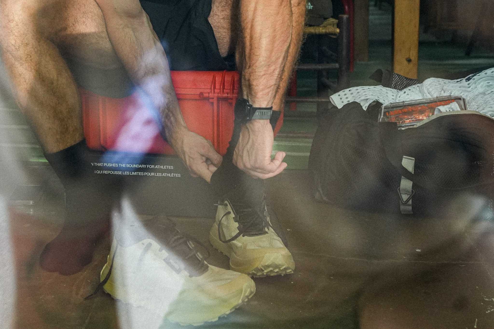 Person tying Norda 055 shoes in reflective setting.